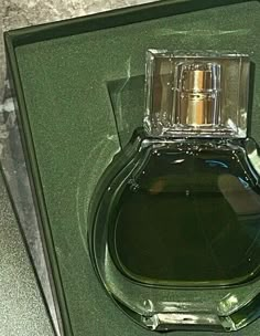 an empty bottle of perfume sitting on top of a green box with its lid open