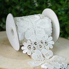 a roll of white lace sitting on top of a piece of wood next to a bush