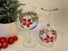 two wine glasses sitting next to each other with christmas decorations on the table behind them