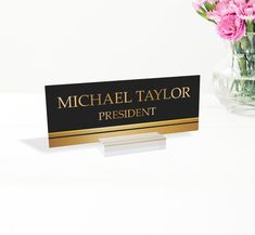 a business card holder with pink flowers in a glass vase on a white table top