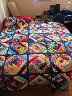 a bed with a colorful quilt on top of it