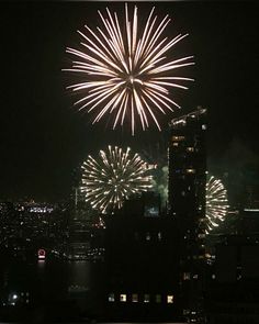 fireworks are lit up the night sky above a large city with tall buildings and skyscrapers