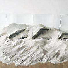 three mirrors sitting on top of a pile of white sand next to a wooden floor