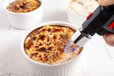 a person is using an electric device to stir food in small white bowls on a table