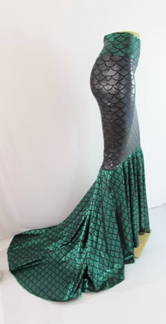 a green mermaid costume on display in front of a white wall