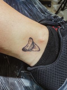 a small tattoo on the ankle of a person's foot, with a mountain in the background