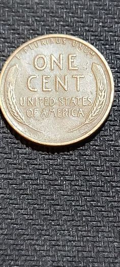 a one cent united states of america coin sitting on a black fabric background with the word,