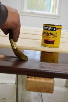 a person painting a wooden bench with a paint can on it and a banana in the foreground