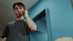 a man talking on a cell phone while standing in front of a blue locker door