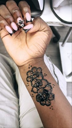 a woman's hand with a black and white flower tattoo on her left wrist