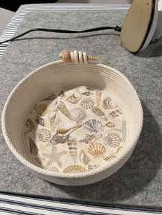 a bowl with shells in it sitting on a table next to a hair dryer