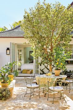 an outdoor dining area with potted plants and tables in front of a bedroom door