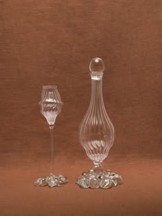 two glass vases sitting next to each other on top of a brown tablecloth