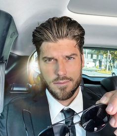 a man in a suit and tie sitting in the back seat of a car wearing sunglasses