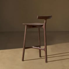 a wooden stool sitting on top of a floor next to a brown wall with shadows