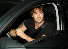 a man sitting in the driver's seat of a car holding a remote control