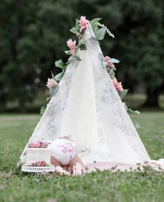 a teepee with pink flowers on it sitting in the grass next to a box