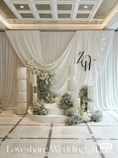 an elegant wedding setup with flowers and candles on the floor in front of white drapes