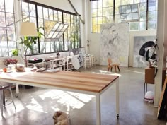 a room filled with lots of furniture and windows next to a dog laying on the floor