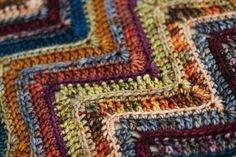 a close up view of a multicolored crocheted blanket with squares on it