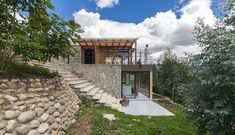 a stone wall and stairs leading up to a house with a glass door on top