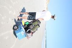 a man is standing on the beach with his luggage