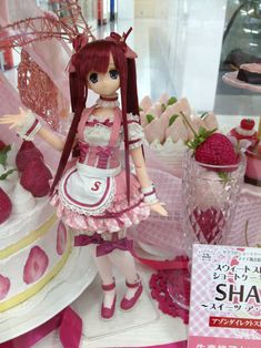 a close up of a doll on a table with strawberries and other items in the background