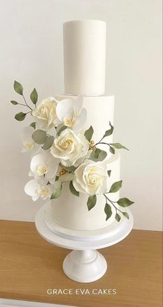 a white three tiered cake with flowers on top