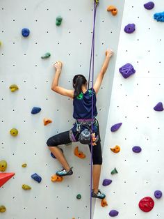 a woman climbing up the side of a rock wall