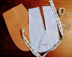 an old pair of scissors and some paper on a wooden table next to a bag