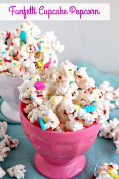 white chocolate popcorn with sprinkles in a pink bowl on a blue tablecloth