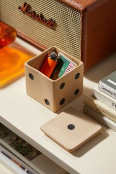 a wooden box with some pens and pencils in it sitting on a table next to books