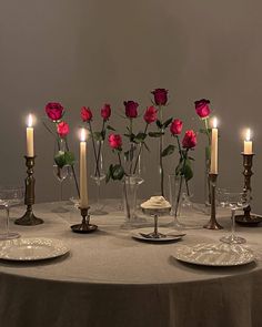 a table topped with candles and vases filled with roses