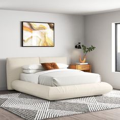 a white bed sitting in a bedroom on top of a wooden floor next to a window