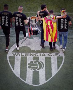 a group of men walking across a soccer field holding onto a yellow and red flag