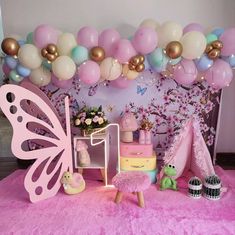 a pink and gold birthday party with balloons on the wall, cake table and decorations