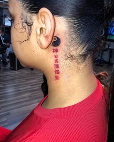 the back of a woman's neck with chinese writing on her left side ear