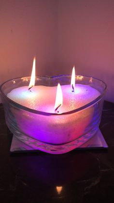 three lit candles in a glass bowl on a table