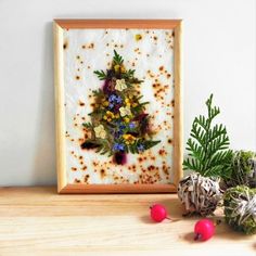 a christmas tree made out of dried flowers in a frame next to some pine cones