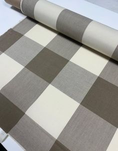 a roll of fabric sitting on top of a table next to a white and brown checkered wallpaper