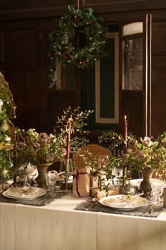 the table is set with flowers and candles on it for an elegant christmas dinner party