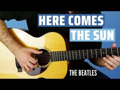 a man holding a guitar with the words here comes the sun