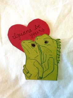 two green lizards holding each other with a red heart