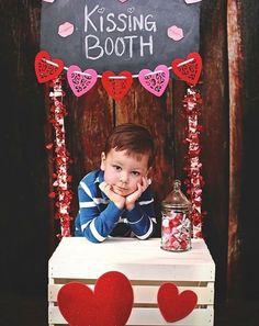 a little boy sitting on top of a table with candy in front of his face