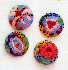 three colorful buttons with flowers on them sitting next to each other in front of a white surface