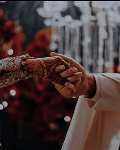 two people holding each other's hands in front of a christmas tree with lights