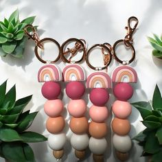 several key chains with different colors and shapes on them next to some green plants in the background