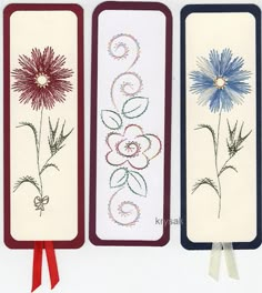 three hand embroidered bookmarks with flowers and swirls on white paper, tied to red ribbon