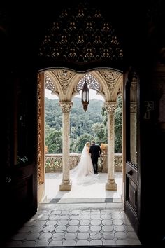 the bride and groom are standing under an archway