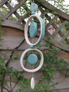 a blue and white wind chime hanging from a wooden fence next to a tree